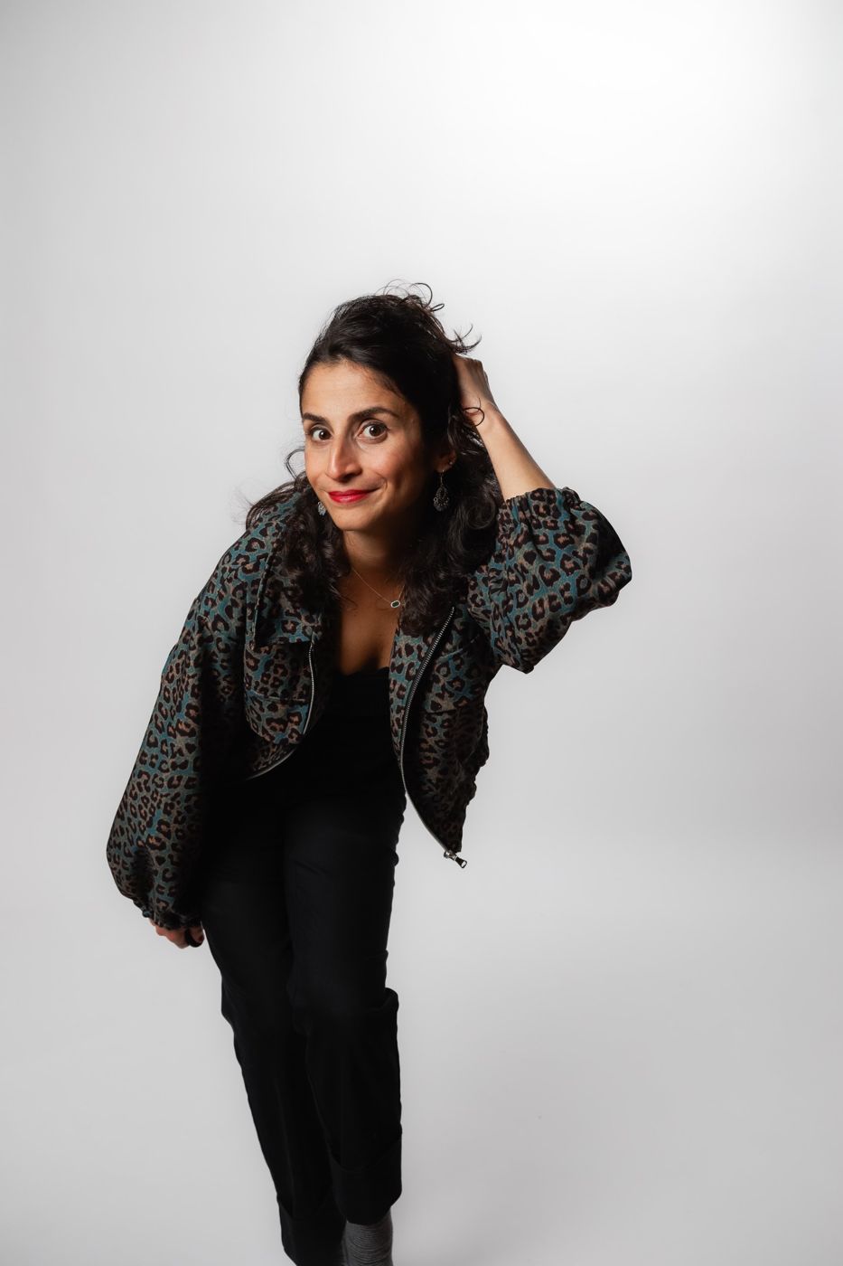 Portrait of Carmen Chraim in a leopard-print jacket, leaning toward the camera with a raised eyebrow